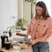A woman slices an avocado in a bright, modern kitchen with natural light.